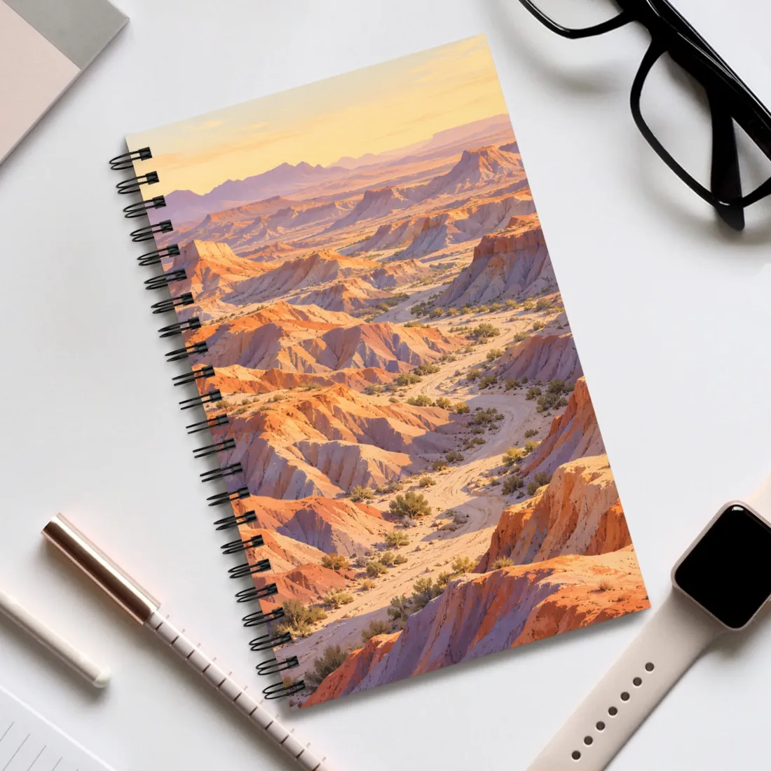 Winding dirt path through orange and lavender badlands canyons at golden sunset – Spiral Notebook, view 2